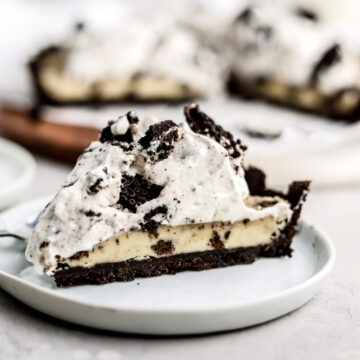 A slice of an Oreo cookie dough tart topped with whipped cream.