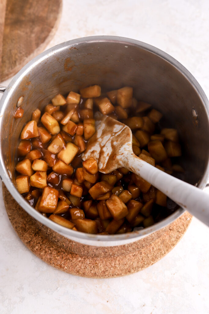 A pot with apple pie filling and a spatula in it. 