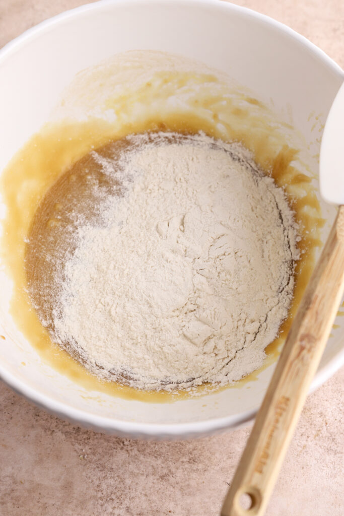 A white bowl with batter and flour in it. 