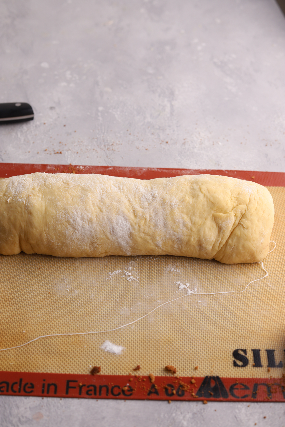 Cinnamon roll dough rolled into a log and some dental floss. 