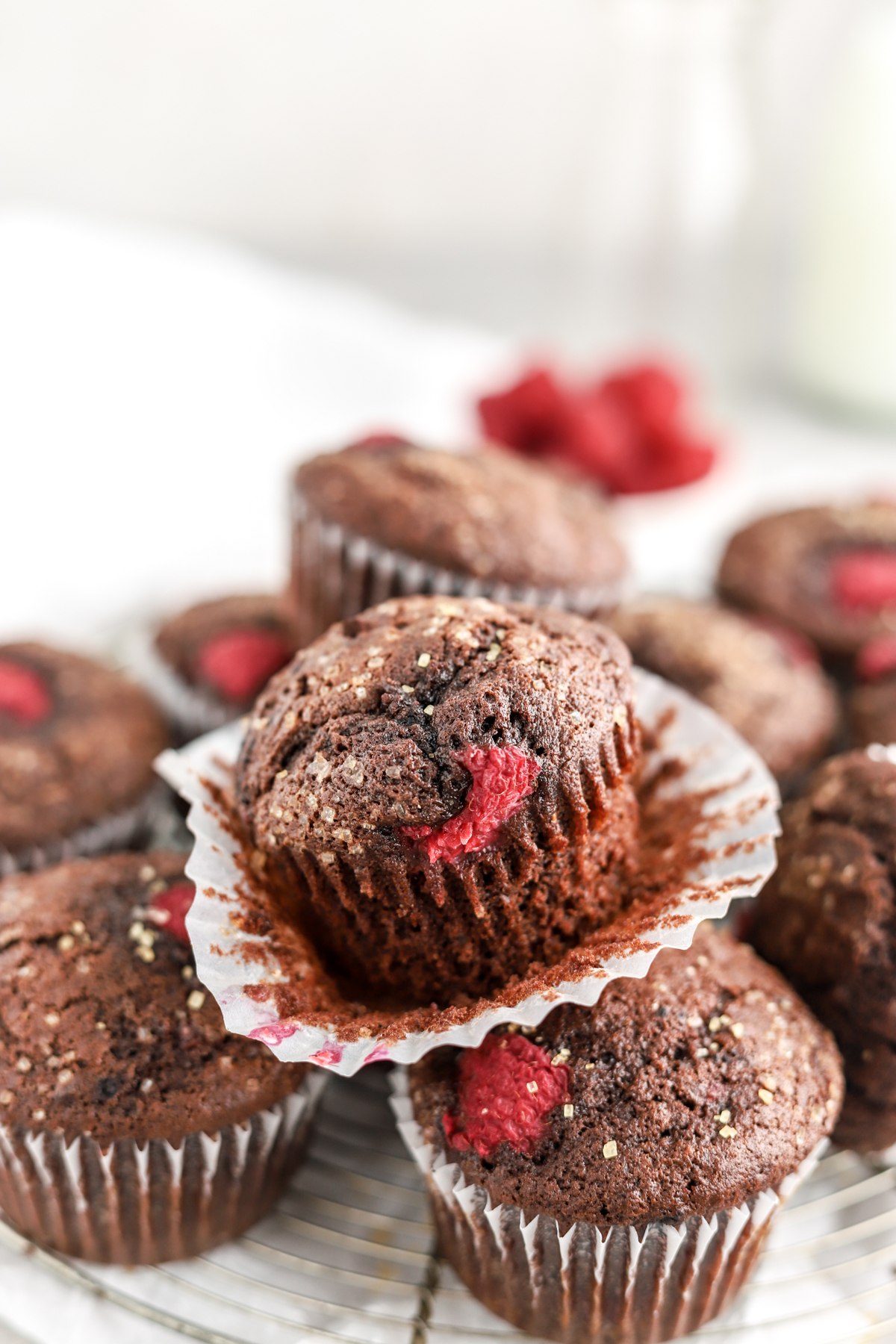 A chocolate raspberry muffin topped with sugar on top of other muffins. 