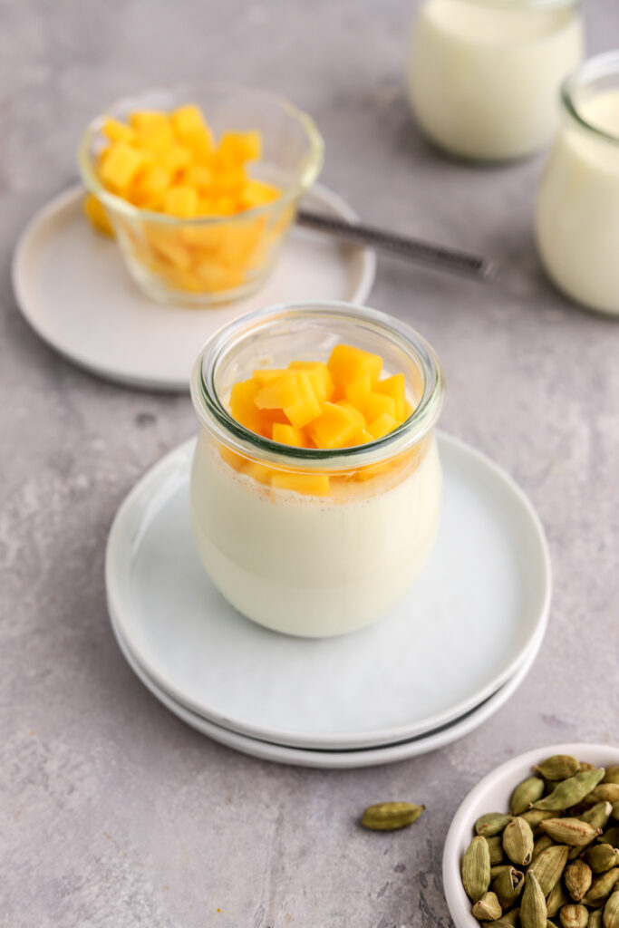 Panna cotta in jars topped with chopped mango.