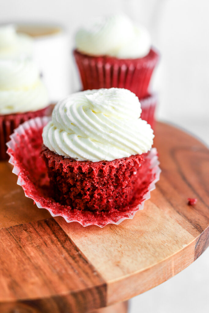 Red velvet cupcakes with cream cheese frosting piped on top.