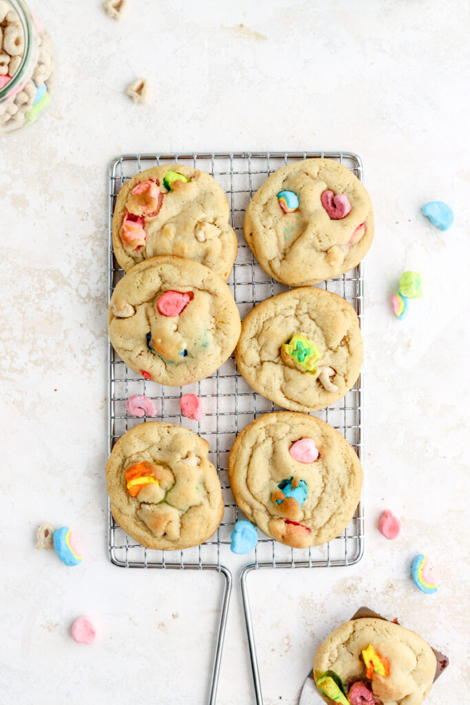 A batch of cookies made with lucky charms marshmallows on a rack.