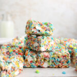 A stack of Fruity Pebbles treats and a milk jug.