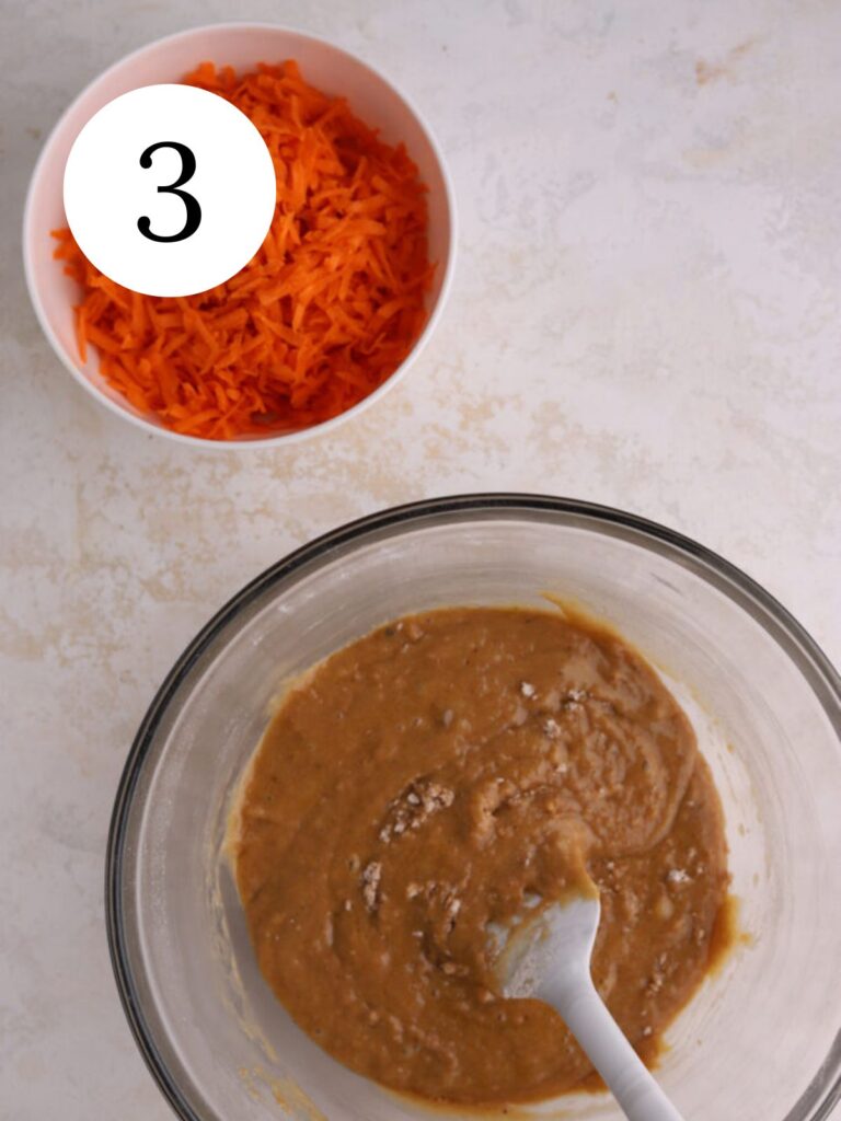 Carrot cake batter in a mixing bowl and a bowl of grated carrots. 