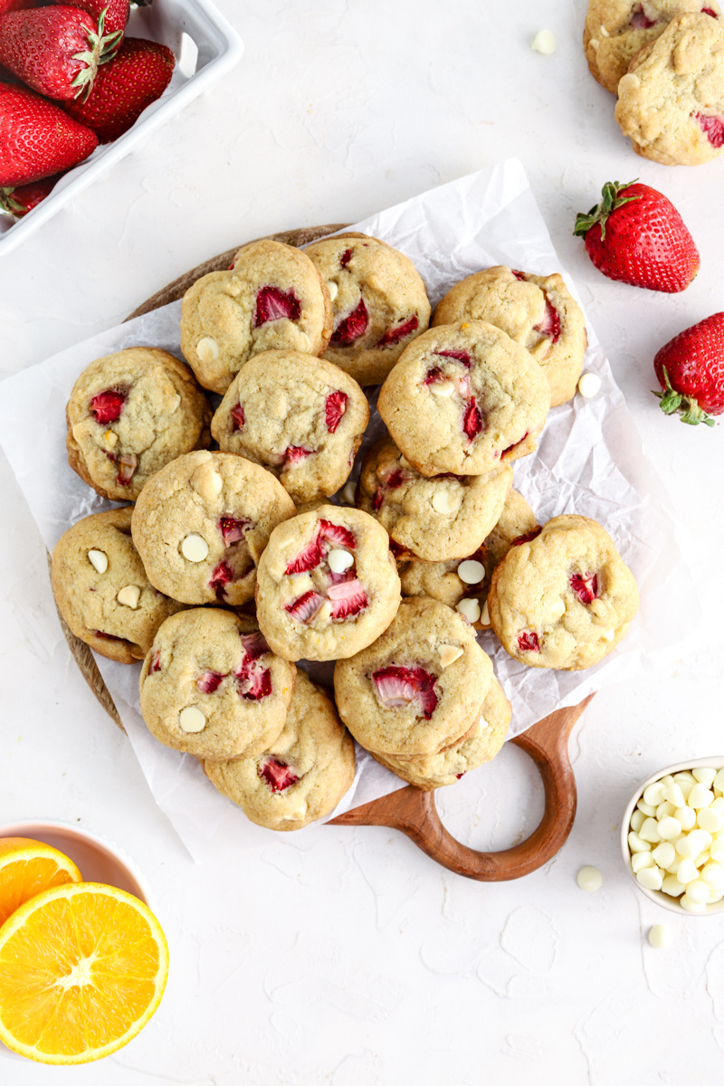 A batch of cookies with strawberries and white chocolate chips on a platter.