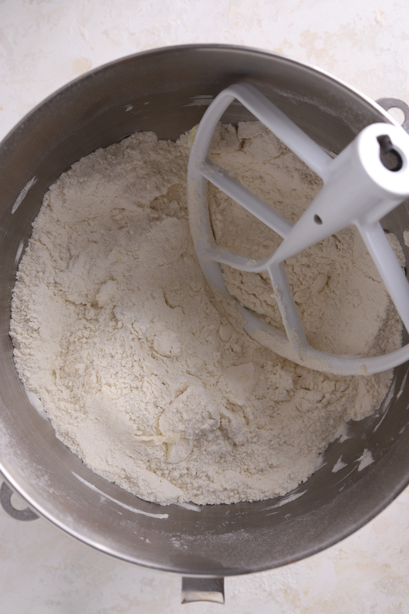 A mixing bowl with flour and butter and a paddle attachment. 