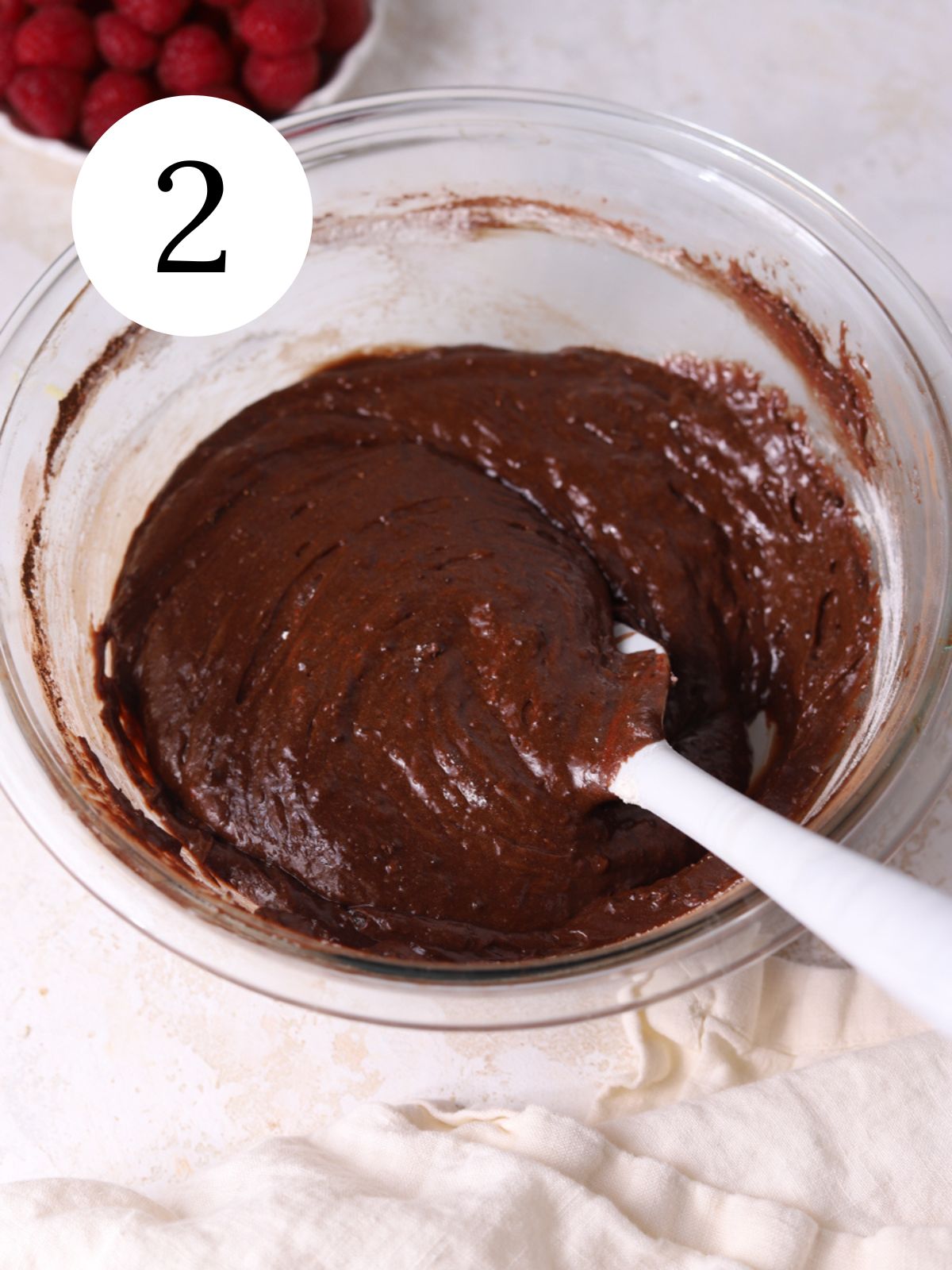 Dry ingredients stirred into chocolate cake batter with a spatula. 