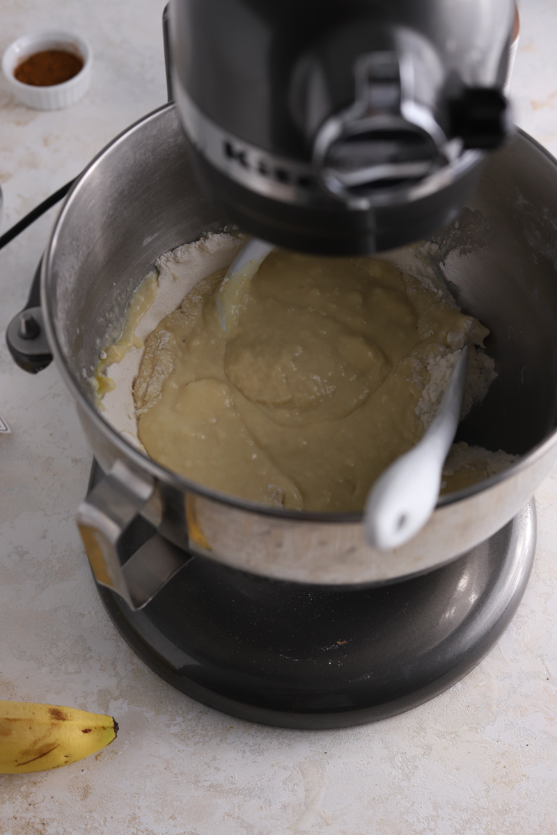 A stand mixer with a dough hook and a spatula and some dough.