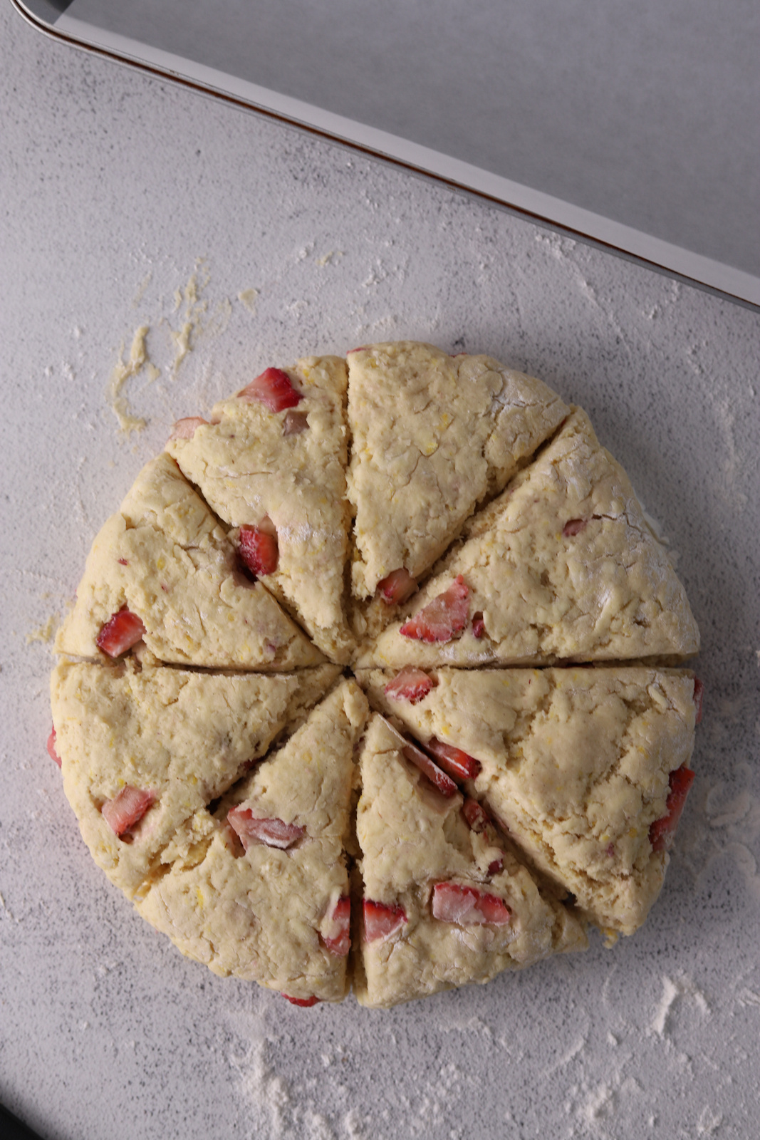 Strawberry scone dough shaped into a circle and sliced in triangles. 