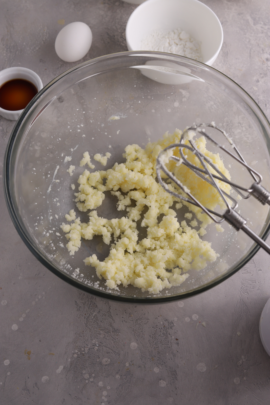 A glass mixing bowl with sugar and butter beaten together. 