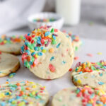 Cookies with colorful Fruity Pebbles baked inside and a milk jug.