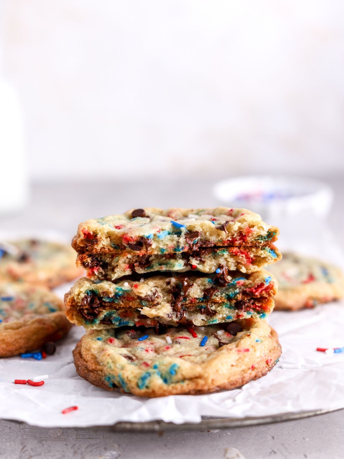 Chocolate chip cookies with red, white and blue sprinkles broken in half and stacked on a cookie.