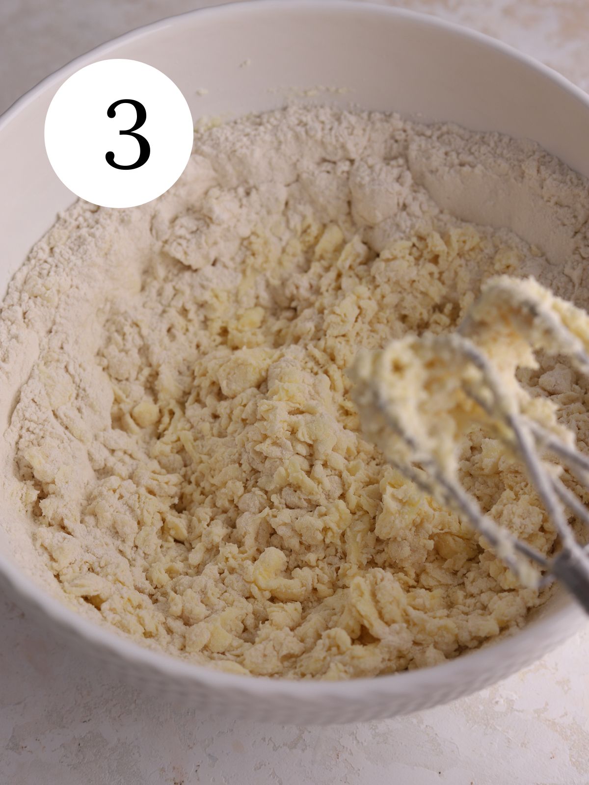 Dry ingredients being mixed into cookie dough with an electric mixer. 