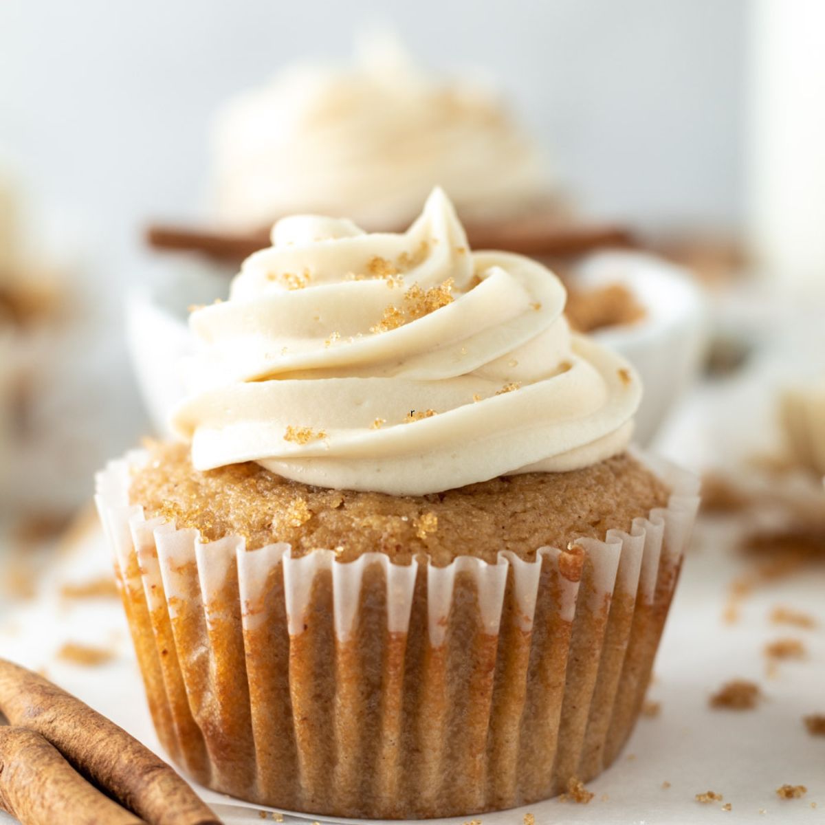 A cupcake topped with a swirl of frosting sprinkled with brown sugar.