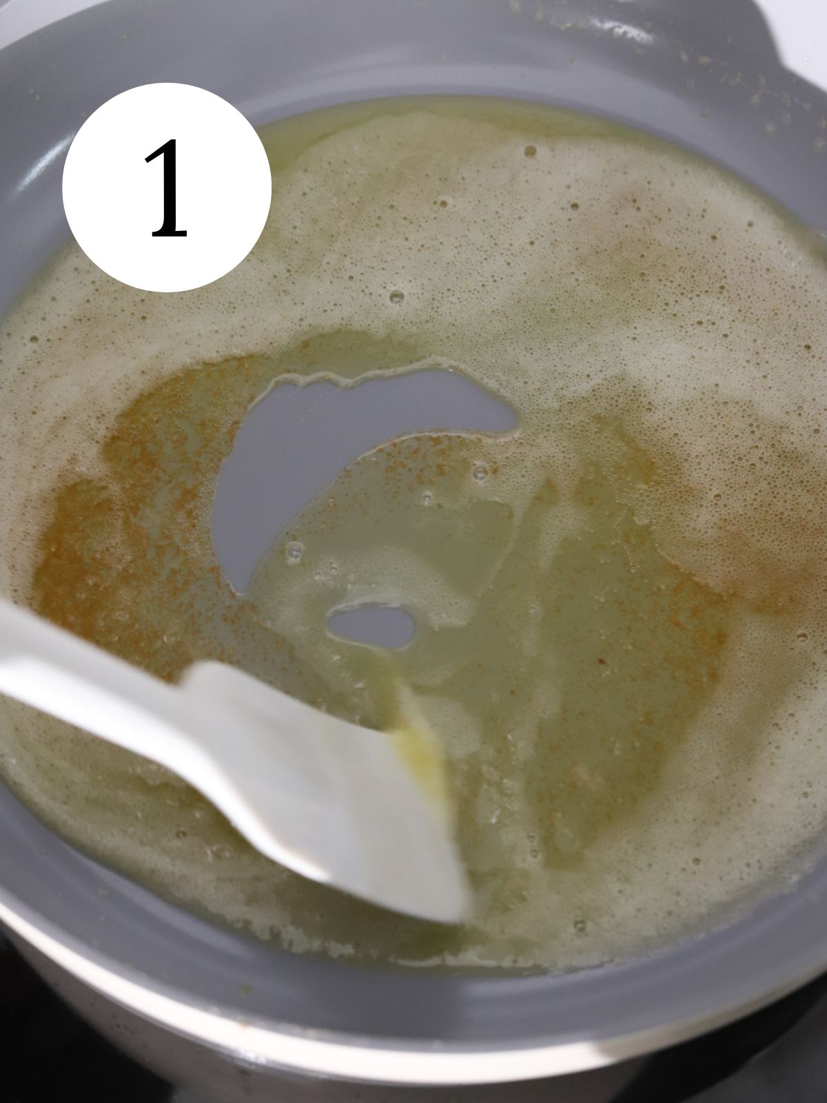 Foamy butter with brown bits in a pan with a spatula. 
