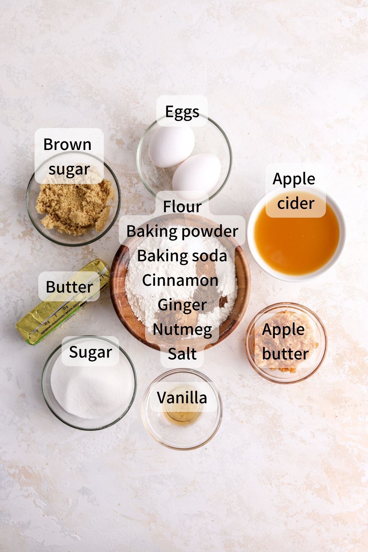 Labeled ingredients needed to make apple cider cookies laid out on a table. 