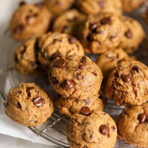 A batch of chocolate chip pumpkin cookies on a rack.