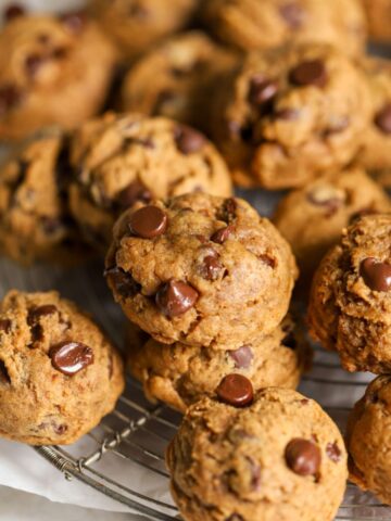A batch of chocolate chip pumpkin cookies on a rack.