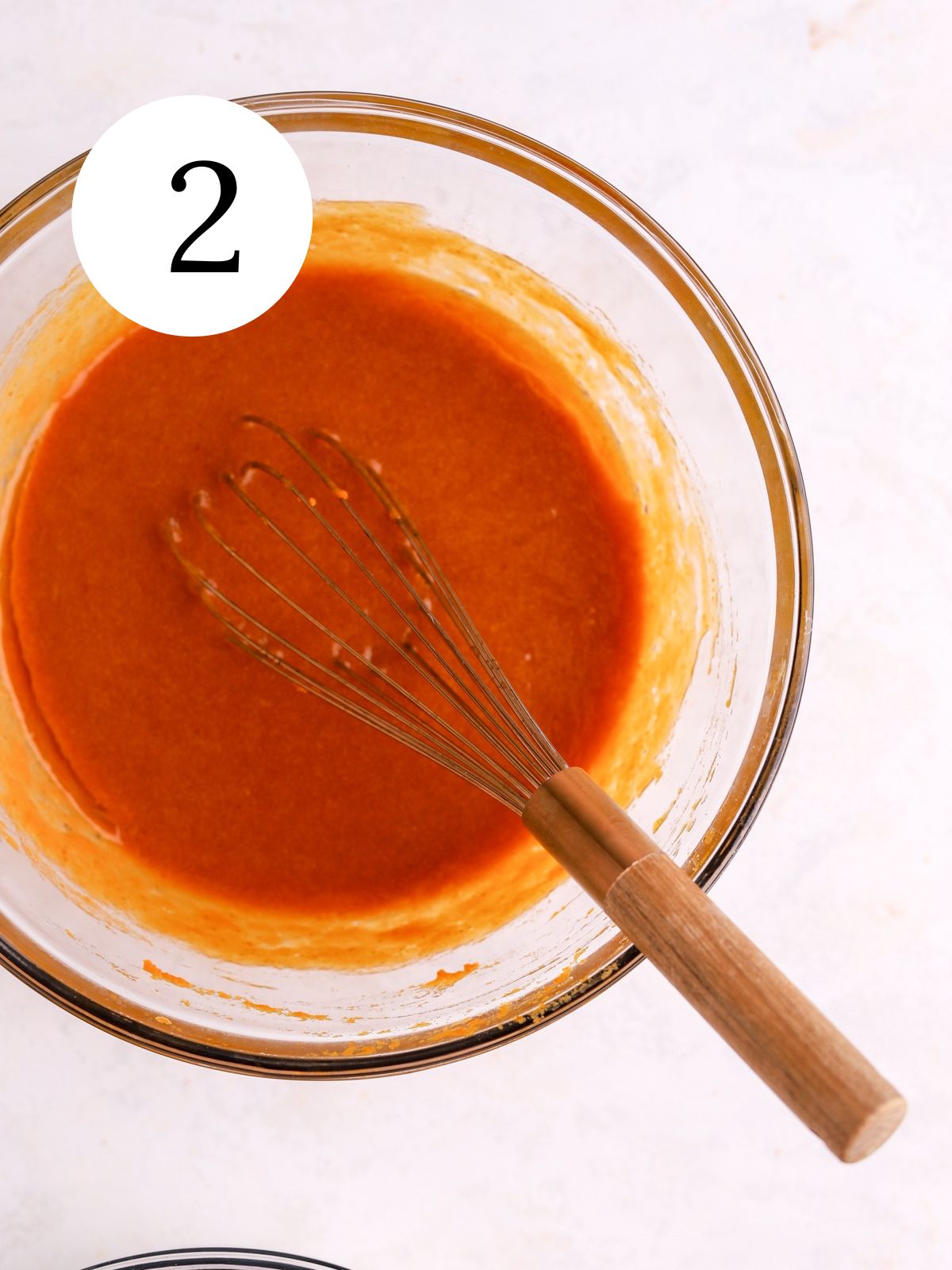 A mixing bowl with pumpkin puree and other wet ingredients whisked together.