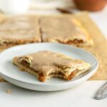 An apple pop tart with a bite taken out of it on a small plate.