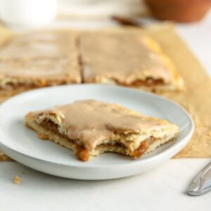 An apple pop tart with a bite taken out of it on a small plate.