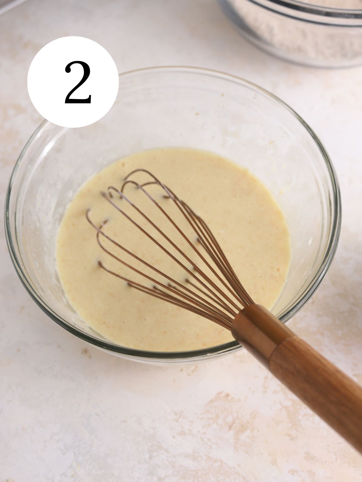 A mixing bowl with batter and whisk. 