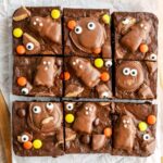 Brownies with monster faces made from peanut butter cups on top cut into slices.