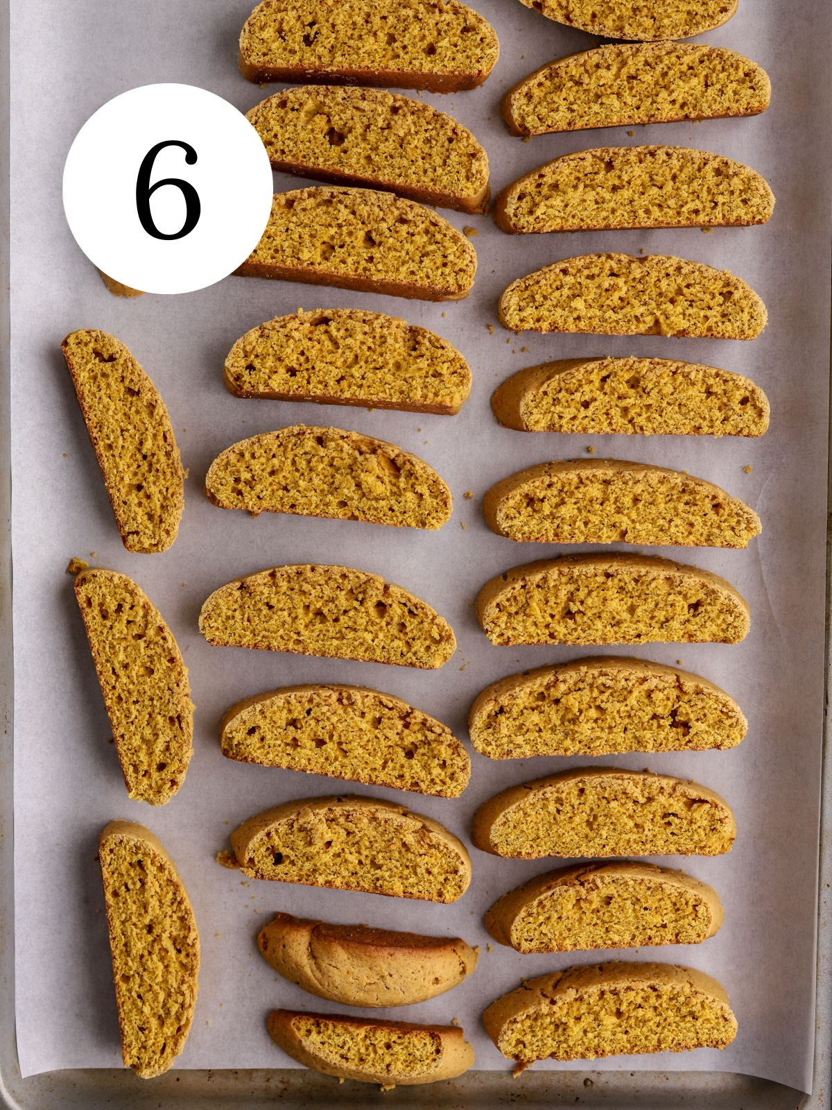 A baking sheet with sliced orange pumpkin biscotti on it.
