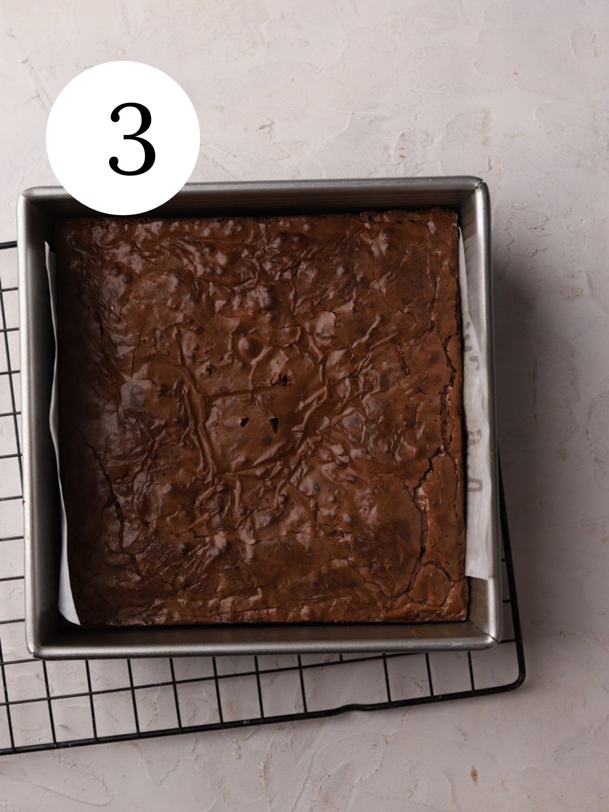 Brownies in a square pan on a wire rack.