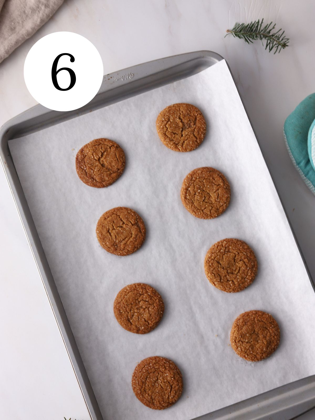 Molasses cookies on a baking sheet lined with parchment paper. 