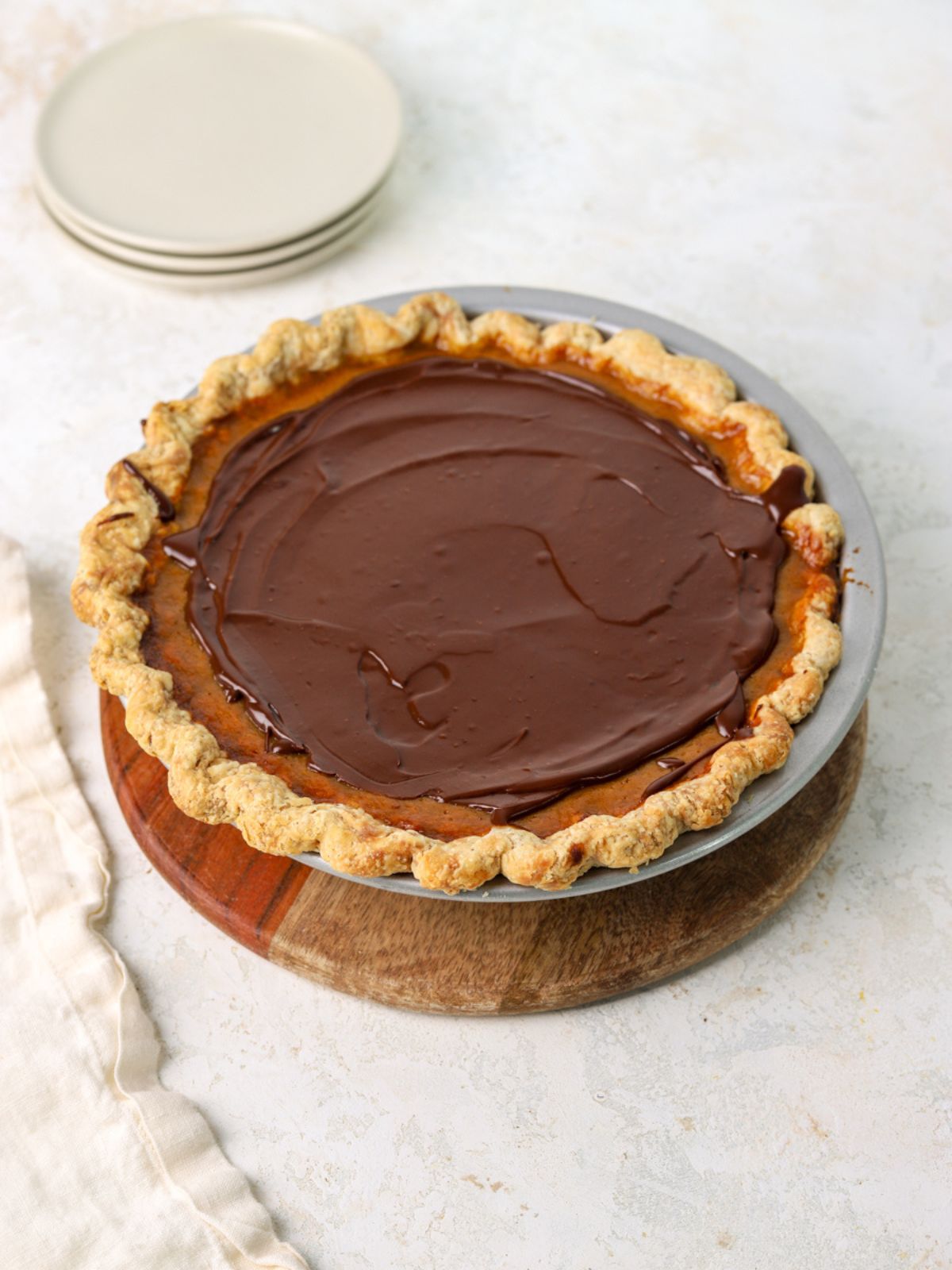 A pumpkin pie with chocolate ganache spread on top.