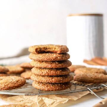 A stack of molasses cookies on a baking rack.