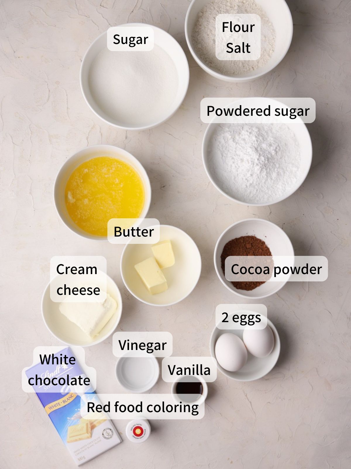 Labeled ingredients needed to make red velvet brownies laid out on a table. 