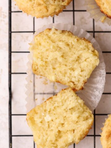 A ricotta muffin cut in half on a wire rack.