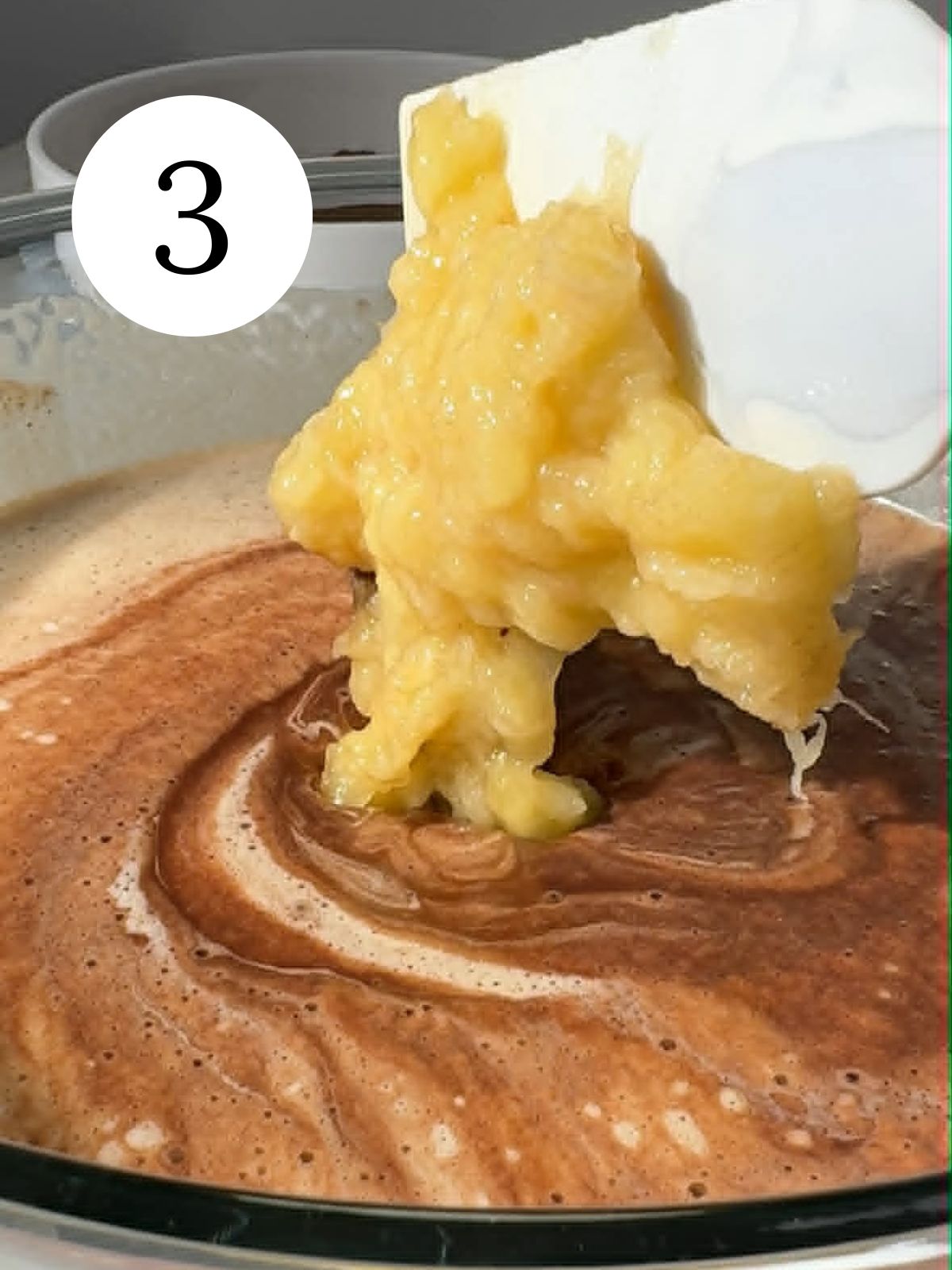 Adding mashed banana to chocolate batter. 