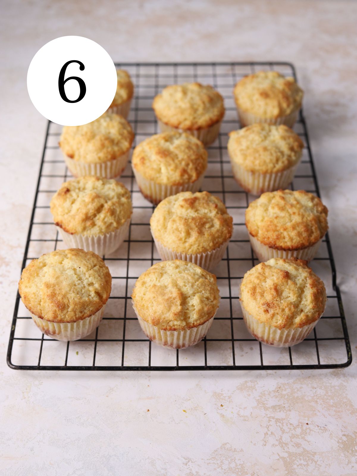 A dozen ricotta muffins on a wire rack.