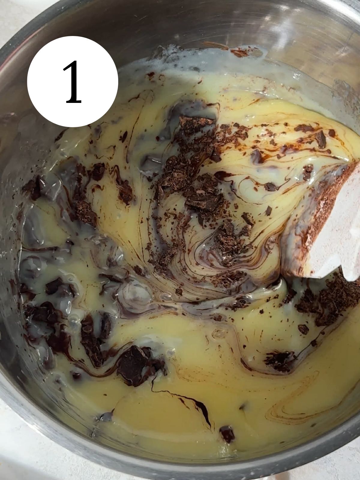 Melted chocolate being stirred into sweetened condensed milk. 