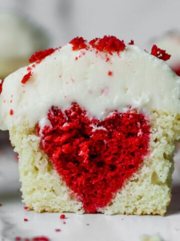 A cupcake sliced in half with a red heart baked inside.