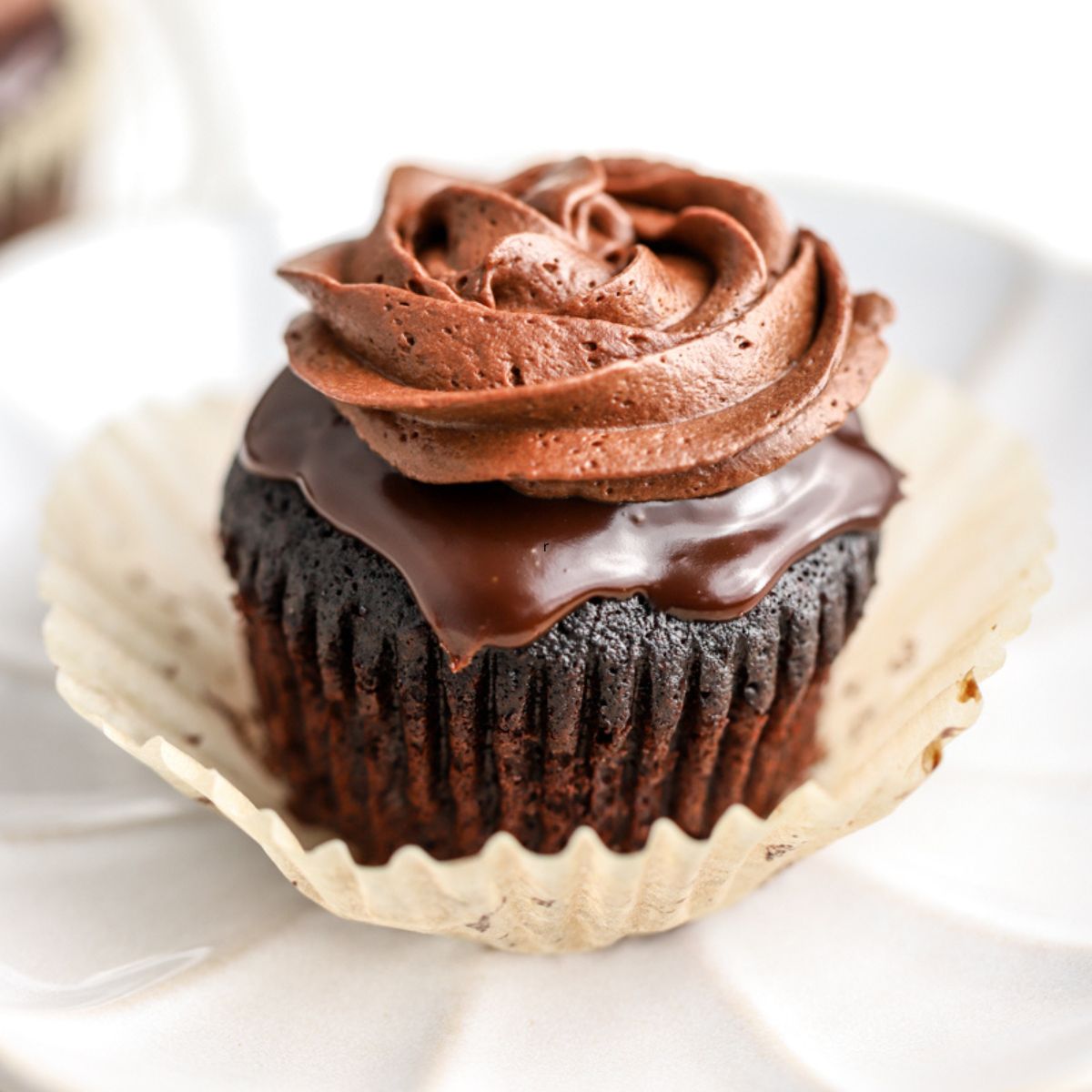 A chocolate cupcake with chocolate ganache piped on top.
