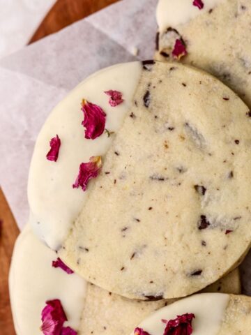 Chocolate shortbread cookies dipped in white chocolate topped with rose petals.