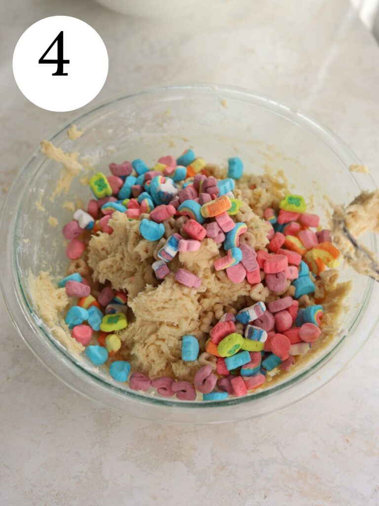 Lucky Charms cereal added on top of a bowl of cookie dough. 