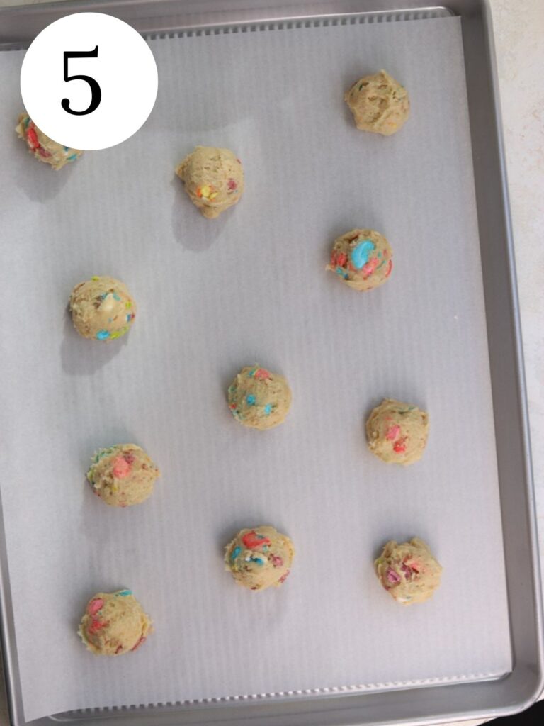 Lucky charms cookie dough balls on a baking sheet lined with parchment paper. 