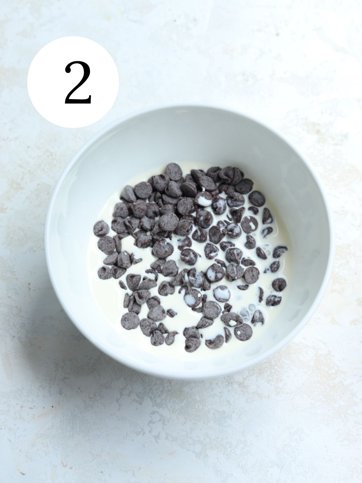 A white bowl with chocolate chips and cream.