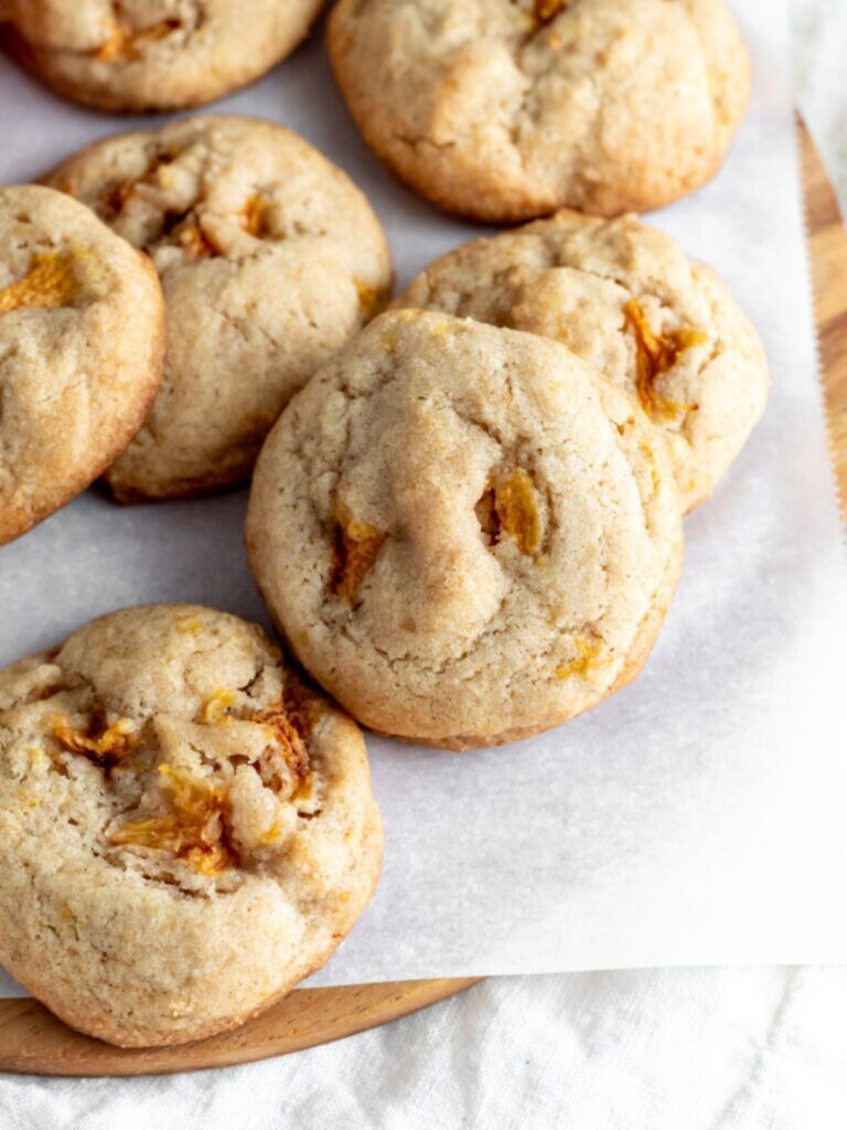Cookies with pieces of peaches baked inside on parchment paper.