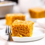 Pieces of golden turmeric cake on white plates.