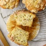 A muffin sliced in half on a rack next to a stalk of rhubarb.