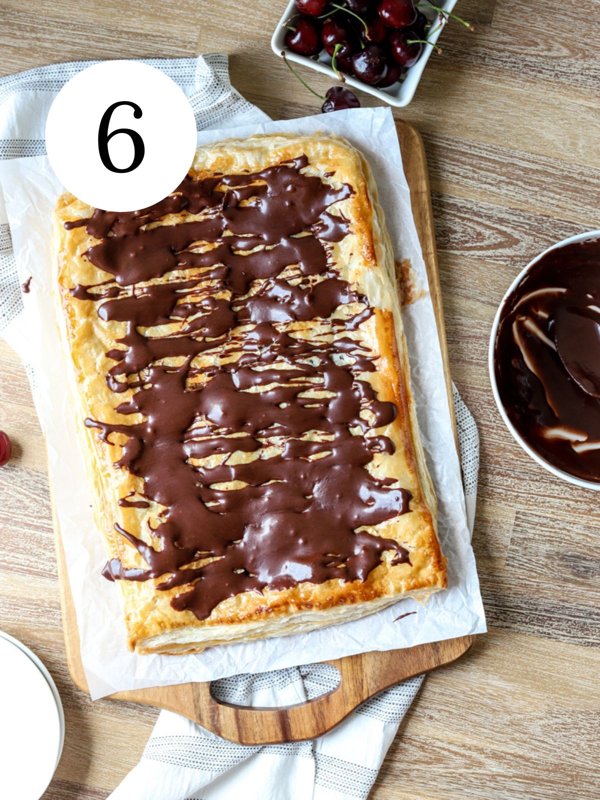 A giant pop tart with chocolate drizzled on top and a bowl of cherries.