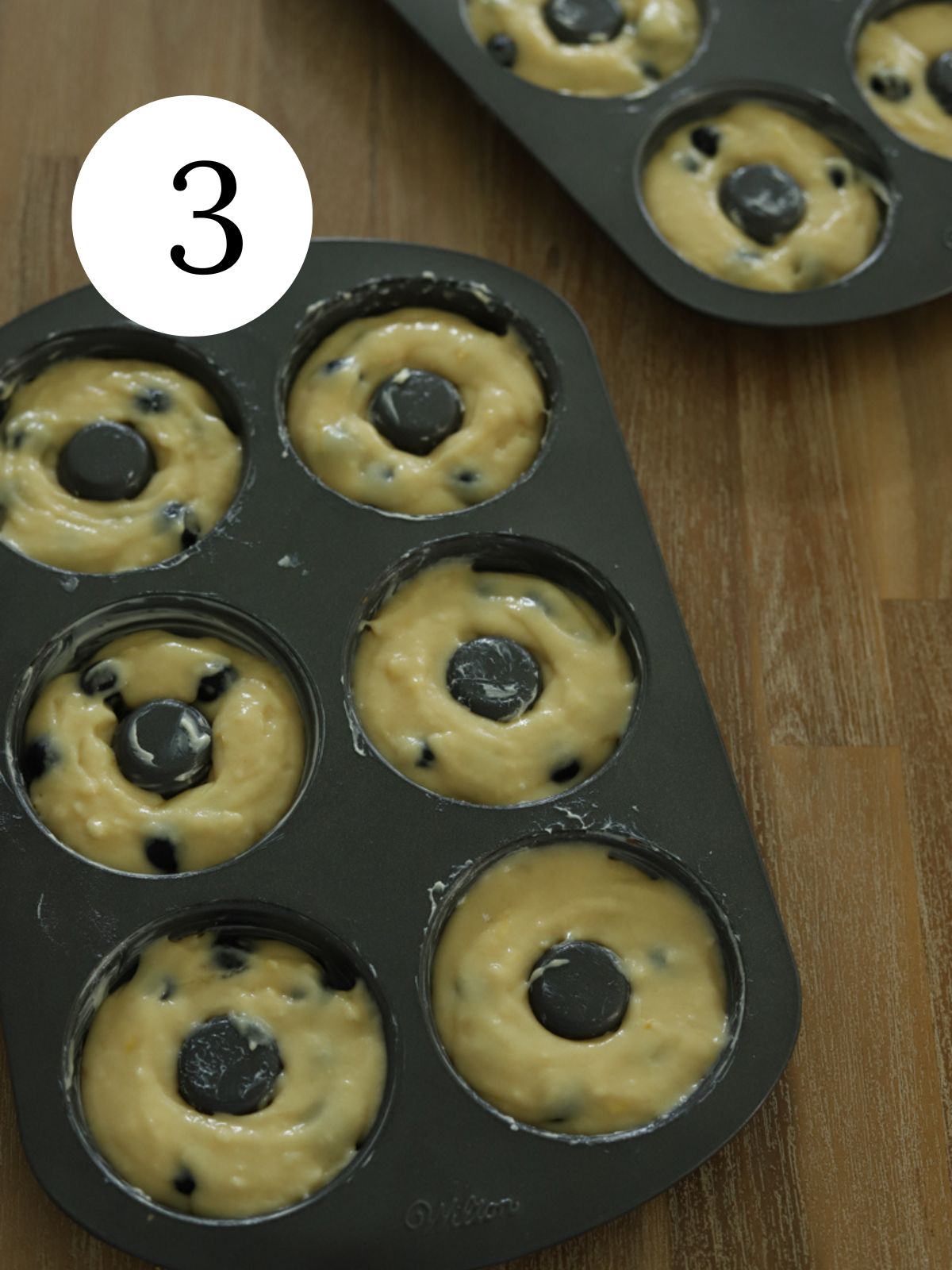 Donut pans filled with blueberry donut batter. 